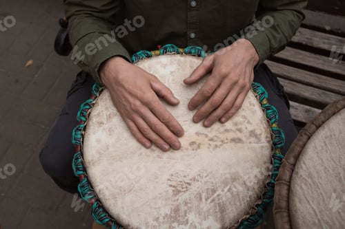 Preview: Male hands playing an African drum djembe outdoors in autumn