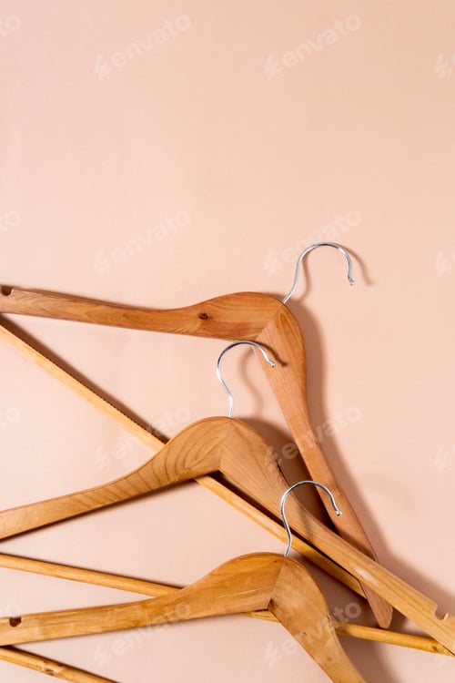 Preview: Top view of wooden hangers lying on a beige background.