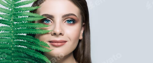 Preview: Beautiful Woman portrait with blue eyes and green plant near face. Organic cosmetic