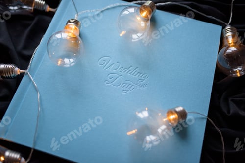 Preview: Blue wedding photo book with the inscription "wediing day" on a black fabric background.