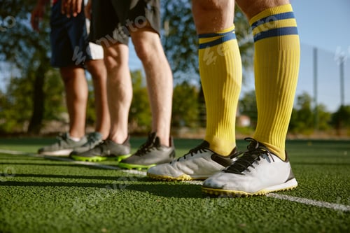 Preview: Football player legs standing on white line dividing football field