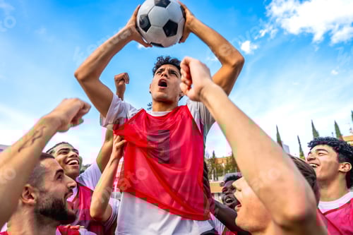 Preview: Soccer team celebrating victory holding ball up high
