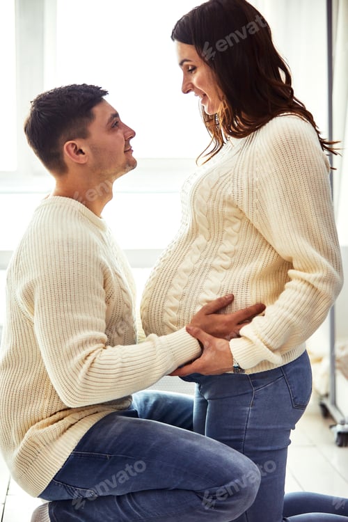 Preview: Close up portrait of expecting teenage couple laughing happily, embracing baby in belly together