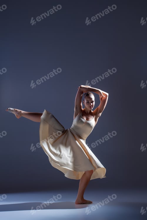 Preview: Young beautiful dancer in beige dress dancing on gray background