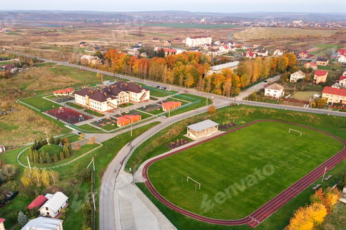 Preview: Aerial view of sports stadium with red running tracks and green grass football field.