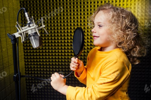 Preview: girl blonde curly hair style star singer artist in a yellow blouse with headphone recording