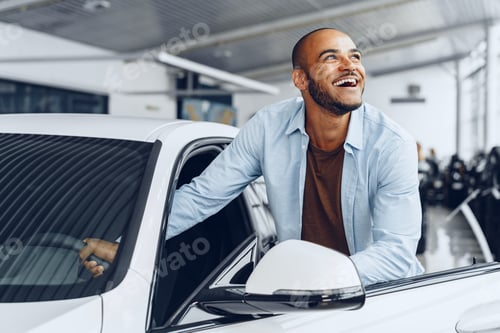 Preview: Portrait of a handsome happy African American man sitting in his newly bought car