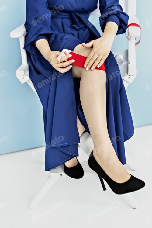 Preview: A woman in a blue dress glues a red medical tape to treat pain in the knee joint. Kinesiotherapy