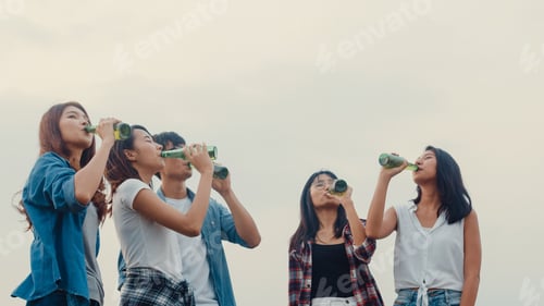 Preview: Asia best friends teenagers salute and cheers toast of bottle beer enjoy party.
