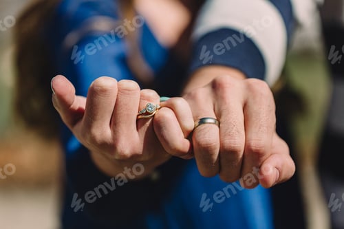 Preview: Two hands linked with wedding rings showing, couple in love, just married newlyweds in sunshine