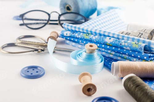 Preview: Sewing accessories and fabric on a white background.