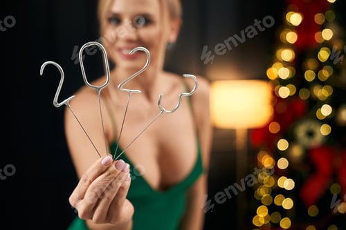 Preview: Blonde woman holding 2023 sparkles, showing.