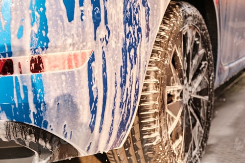 Preview: Close up a wheel of a blue car washing under high pressure with foam . Manual car washing self