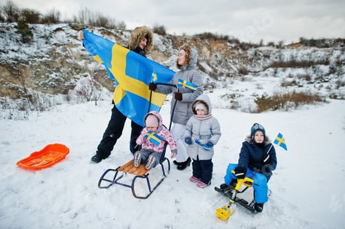 Preview: Scandinavian family with Sweden flag in winter swedish landscape.