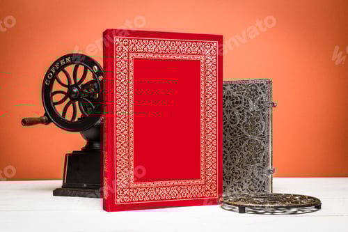 Preview: Crafting memories with a red notebook, vintage press, and intricate metal decor on a warm background