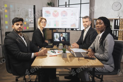 Preview: Skillful businesspeople looking at the camera while having video conference from laptop in boardroom