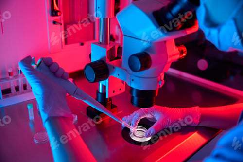 Preview: Adult doctor preparing a sample for analysis under vibrant lights