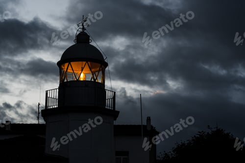 Preview: Shining lighthouse against cloudy sky