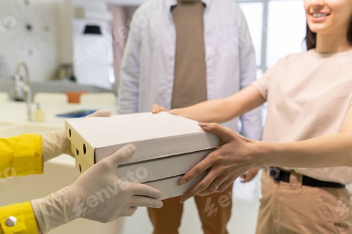 Preview: Gloved hands of courier passing stack of boxes with pizza