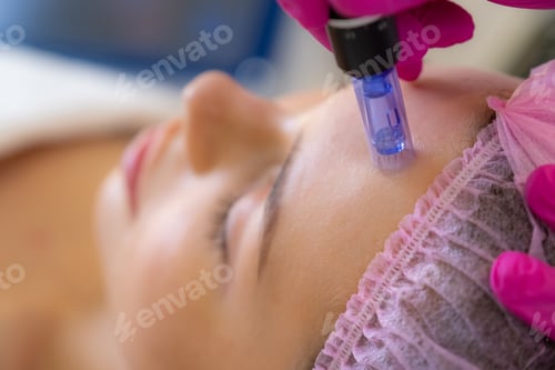 Preview: Cosmetologist making a woman a therapeutic laser processing on a face.
