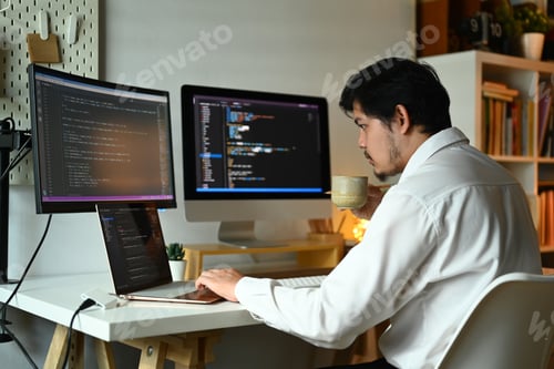 Preview: Concentrated male web developer working with coded data on computer screen.
