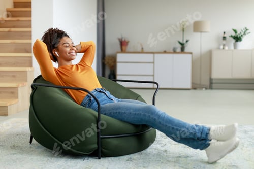 Preview: Calm black woman having rest at home on bean bag