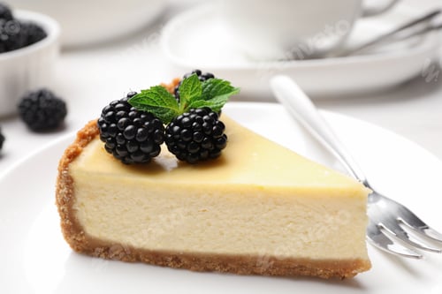 Preview: Piece of delicious cheesecake decorated with blackberries on table
