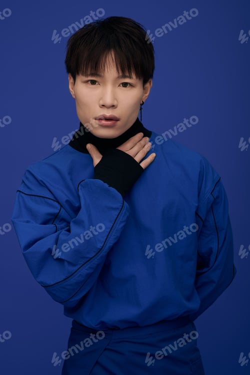Preview: Expressive young asian man in striking blue attire against a vibrant backdrop