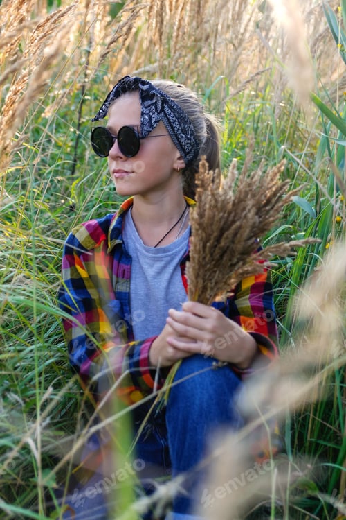 Preview: teen or preteen girl walking on nature background. Little kid girl holding bunch of pampas grass. Gr