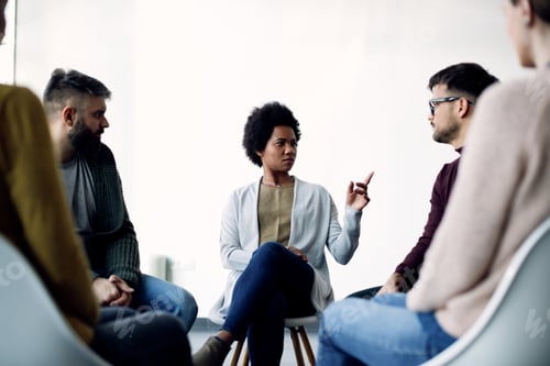 Preview: Mid adult black woman communicating with support group during psychotherapy.