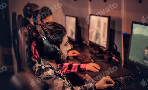 Team of teenage gamers plays in a multiplayer video game on pc in a gaming club.