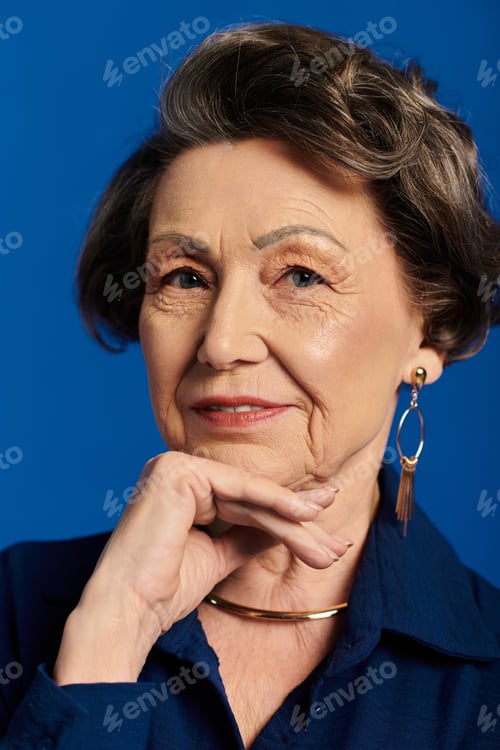 Preview: A beautiful woman in her 60s showcases her style and confidence on a vibrant blue background.