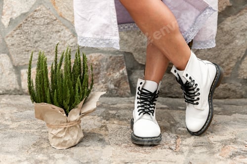 Preview: Female legs in rough white boots and potted plant
