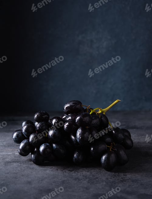Preview: a cluster of juicy black grapes lies on a dark gray table