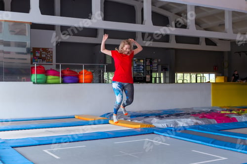 Preview: Fitness, fun, leisure and sport activity concept - Young happy woman jumping on a trampoline indoors