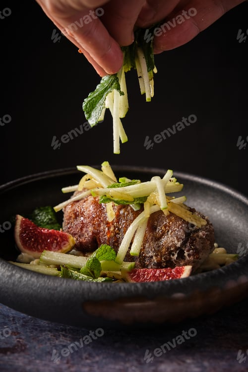 Preview: Crop person adding chopped veggies to pig trotter