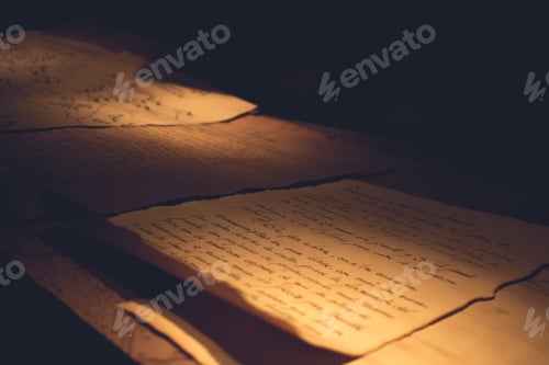 Preview: Closeup of writings written on old parchment papers on a wooden surface with a dark background