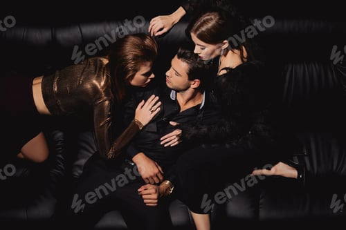 Preview: top view of attractive women kissing and hugging handsome man on black background