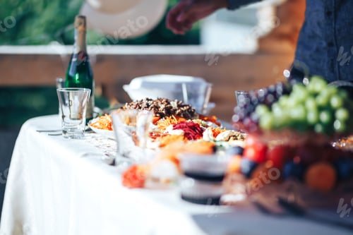 Preview: Long table covered with a tablecloth on which there is a lot of food, food in plates