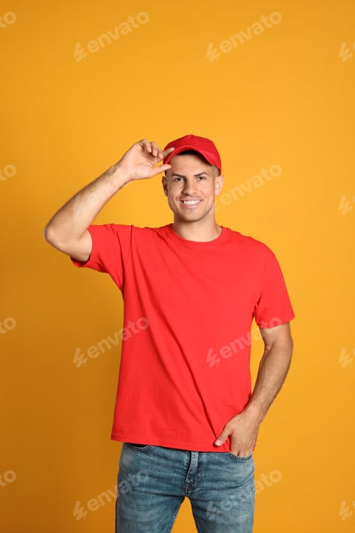 Preview: Smiling Man Adjusting Red Cap on Yellow Background