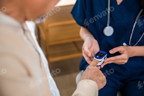 Preview: Young woman putting digital oximeter of finger middle aged adult patient for measurement