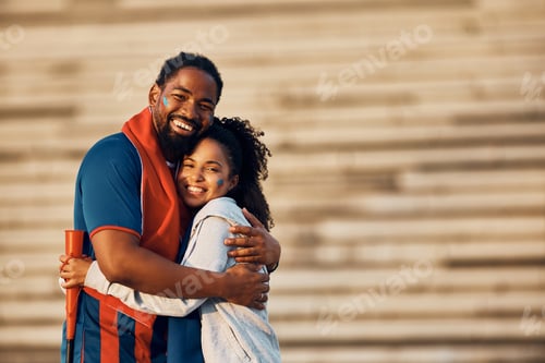 Preview: Happy black couple of sports fans embracing outdoors and looking at camera.