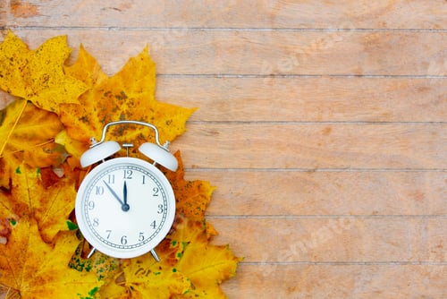 Preview: Alarm clock and maple leaves on wooden table