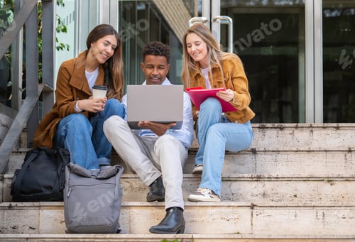Preview: University students working together on a project using laptop outdoors