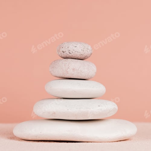 Preview: Close up view of stacked zen stones on sand isolated on peach