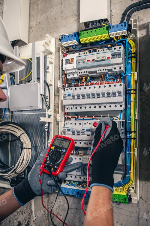 Preview: Man, an electrical technician working in a switchboard with fuses.