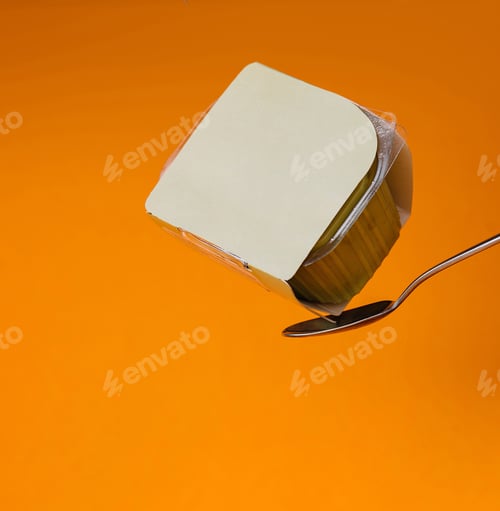 Preview: Yogurt cup balanced on spoon against orange background