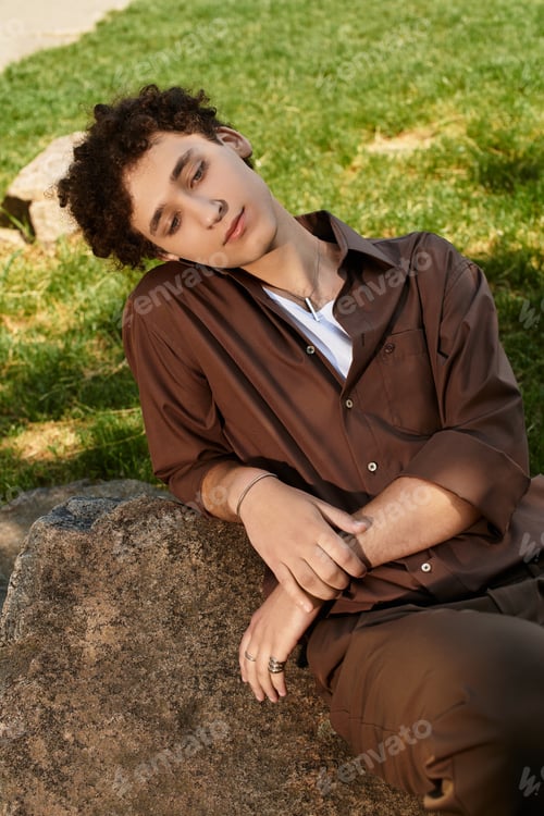 Preview: Stylish young man relaxing in a green park during a sunny summer day