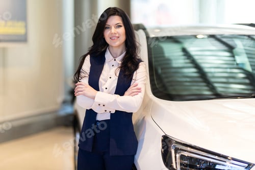 Preview: Beautiful saleswoman possing near new car in dealership center