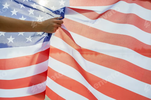 Preview: Human hand holding USA national flag. Celebration of United States independence day concept.